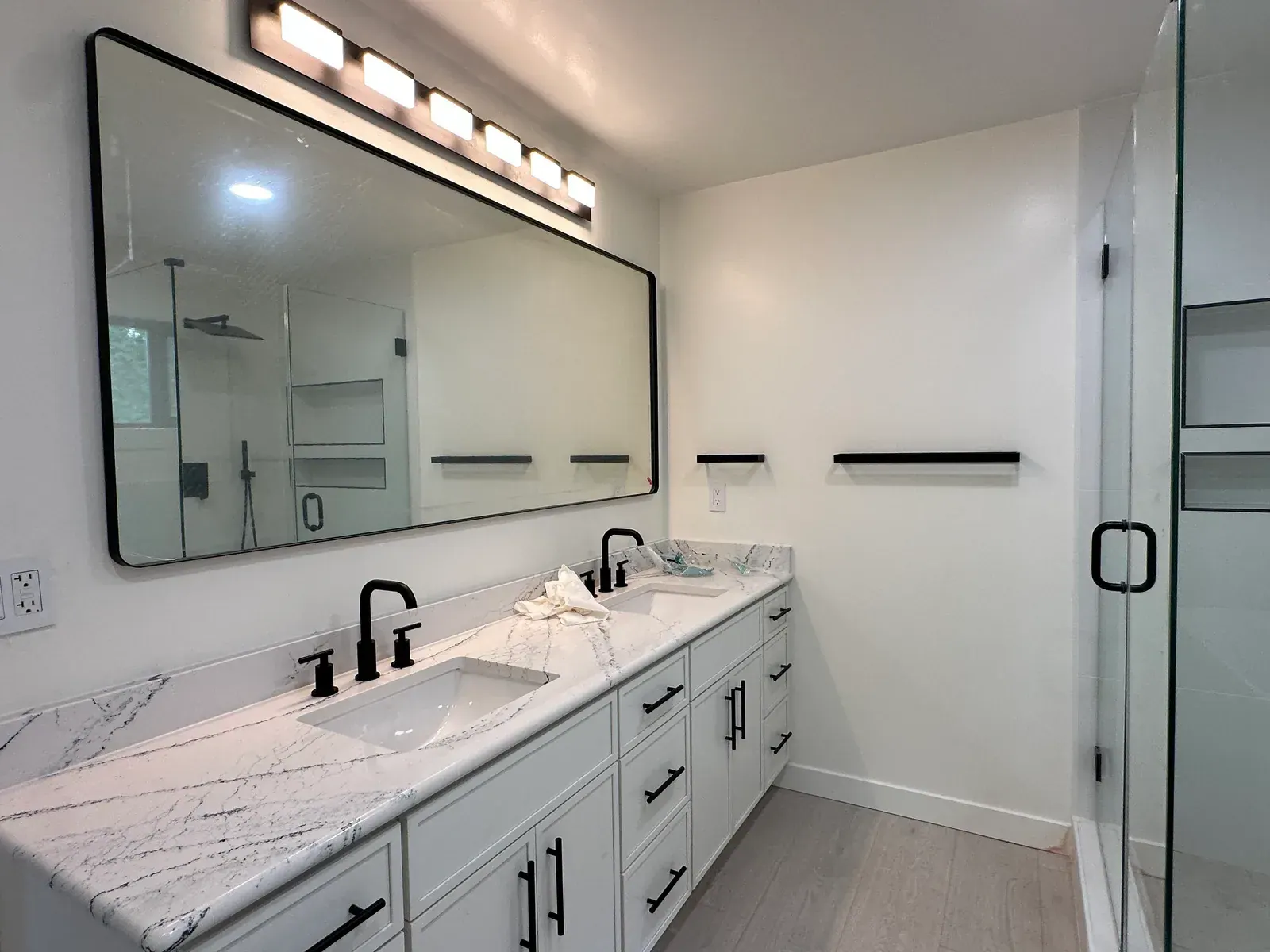 Finished Redmond primary bathroom with a double vanity, quartz counters, and glass shower