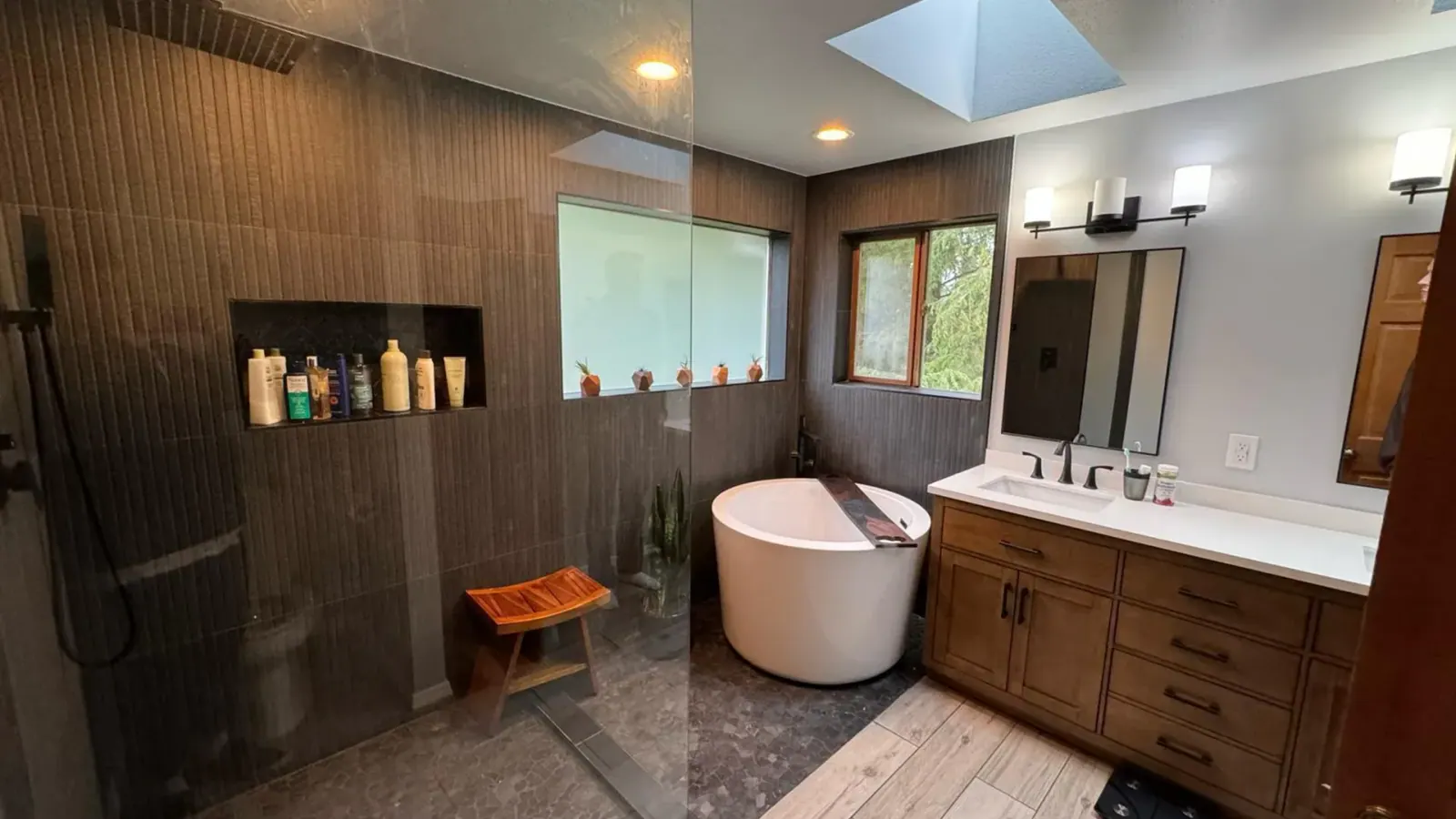 Finished Renton basement bathroom with glass shower, freestanding tub, and wood vanity